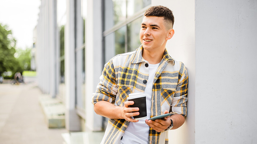 Man holds phone and coffee cup