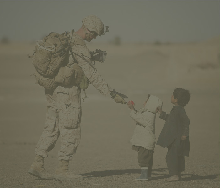 A marine in the marine corps reserve hands food to child