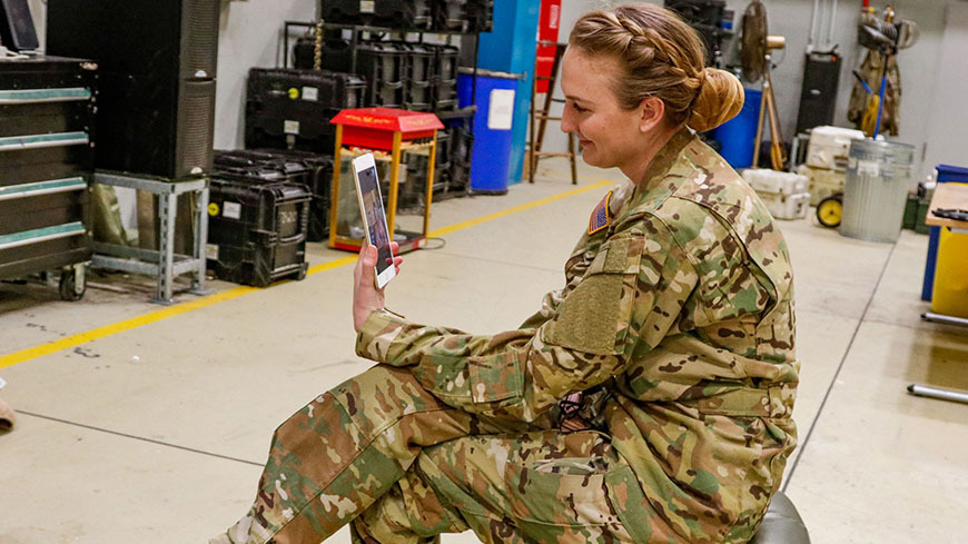 Military woman in uniform looks at phone