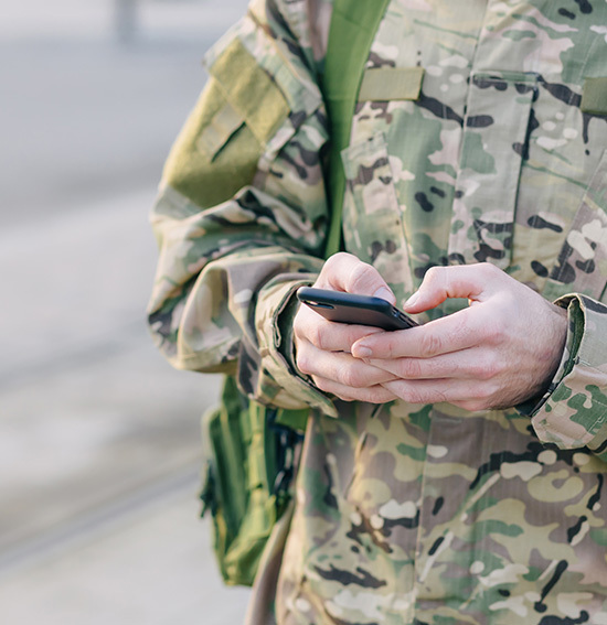 Military man holds cell phone